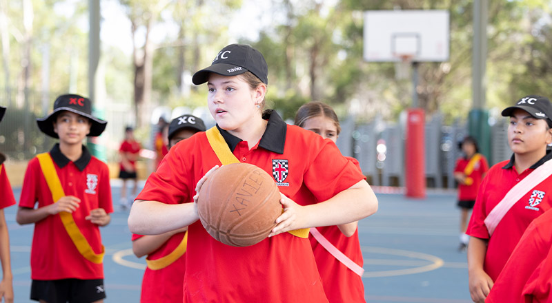 Students playing basketball on the basketball court at Xavier College Llandilo
