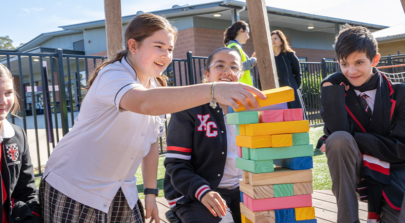 Students playing giant jenga in the playground at Xavier College Llandilo