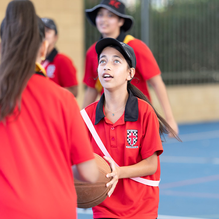 Students playing basketball together in the playground at Xavier College Llandilo
