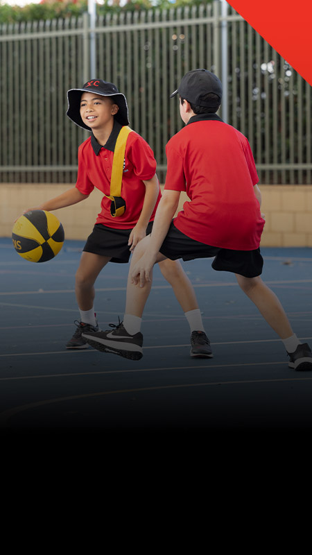 Students playing basketball on the school basketball court at Xavier College Llandilo