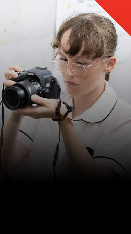 Student taking photos with a camera in the classroom at Xavier College Llandilo